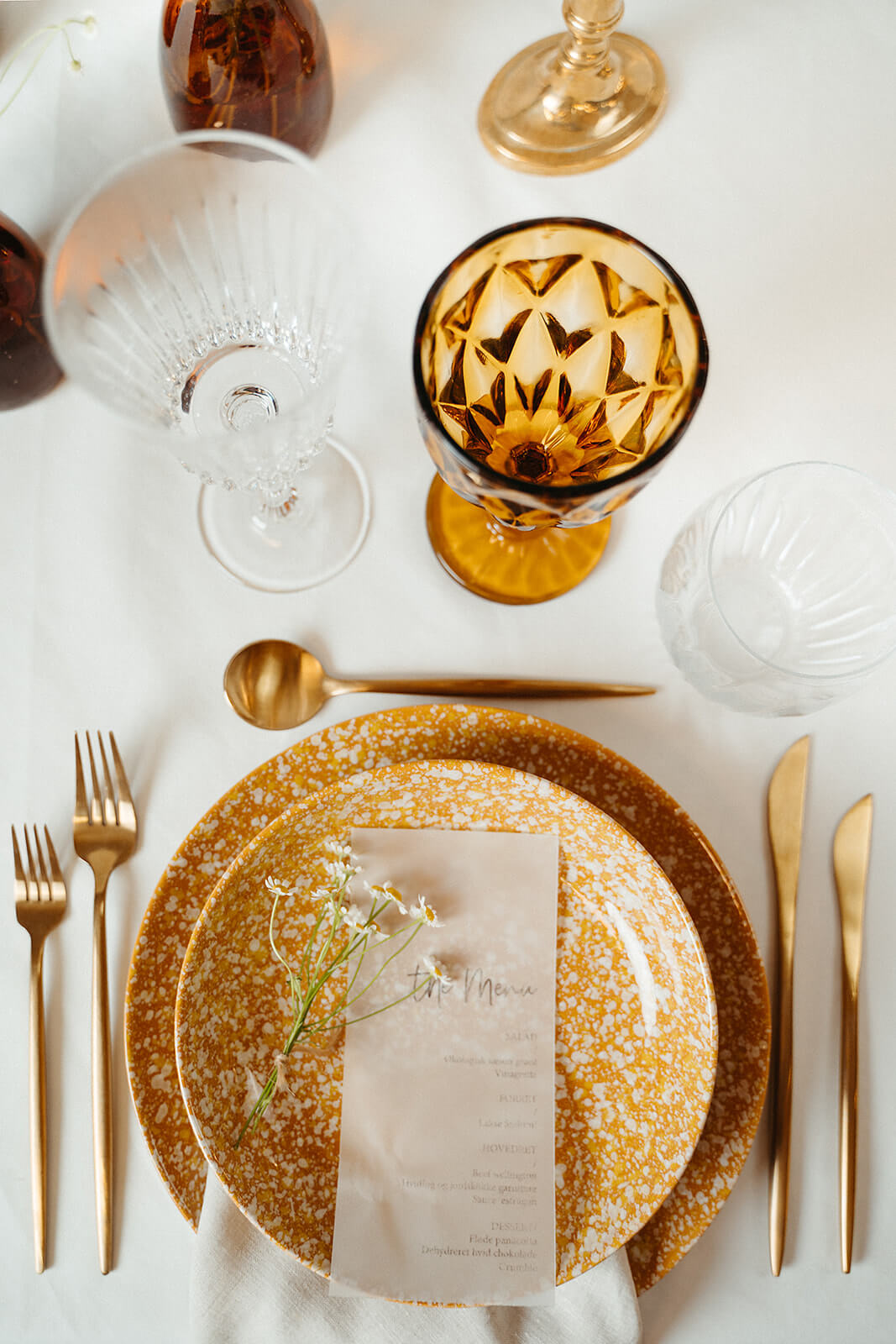 borddækning med Carmel stel og. amberfarvet vinglas og messing bestik