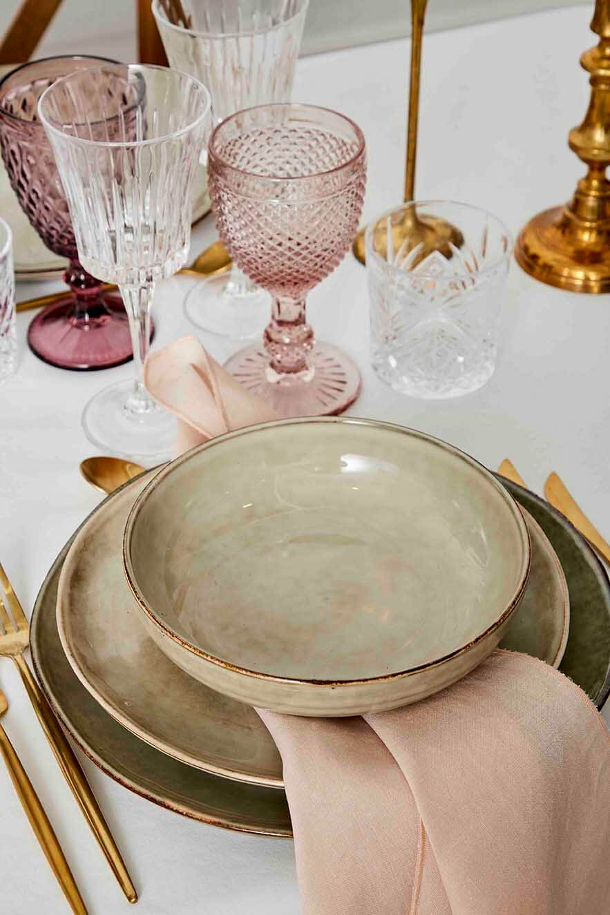Borddækning med keramik og et rosa vinglas
