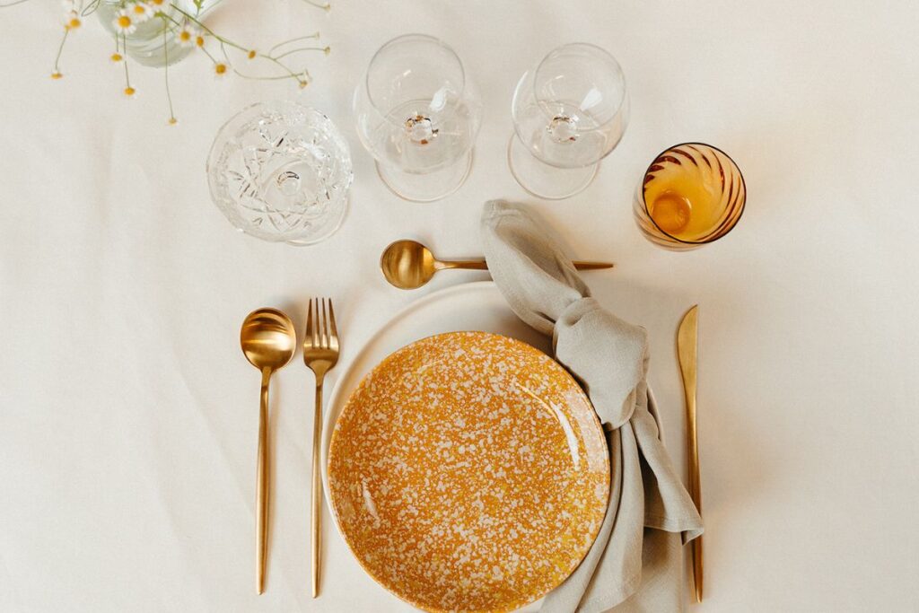 carmel stel med hvid churchill tallerken gyldbestik og amberfarvet vandglas og. natur hørserviet